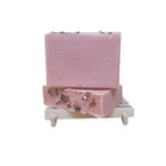 Pink soap bar with decorative roses on top against a white background