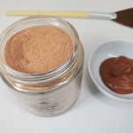 chocolate bliss face mask hydrated in dish next to fan brush