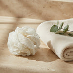 Natural ramie body pouf styled on a spa surface