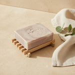 Rectangular wooden soap dish holding a bar of handmade soap