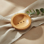 Round wooden soap dish resting on natural linen