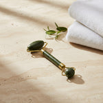 Jade facial roller resting on stone