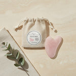 Rose quartz gua sha with its linen pouch and massage guide