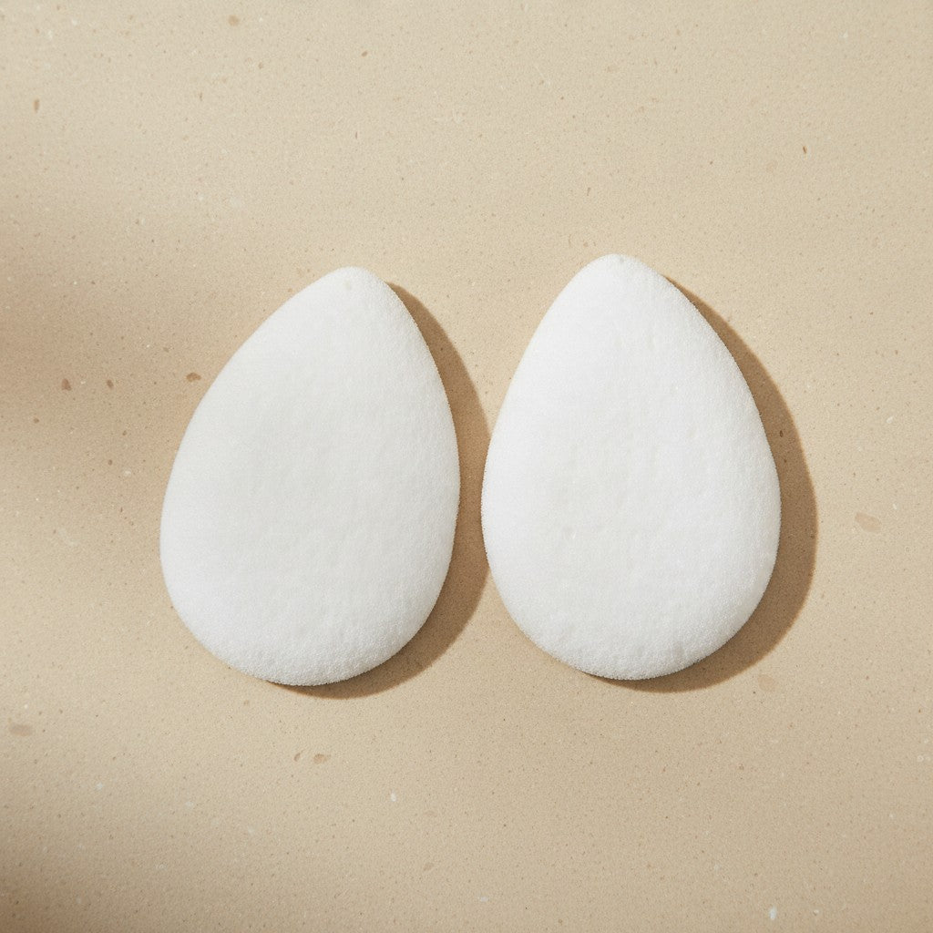 Two white teardrop facial sponges