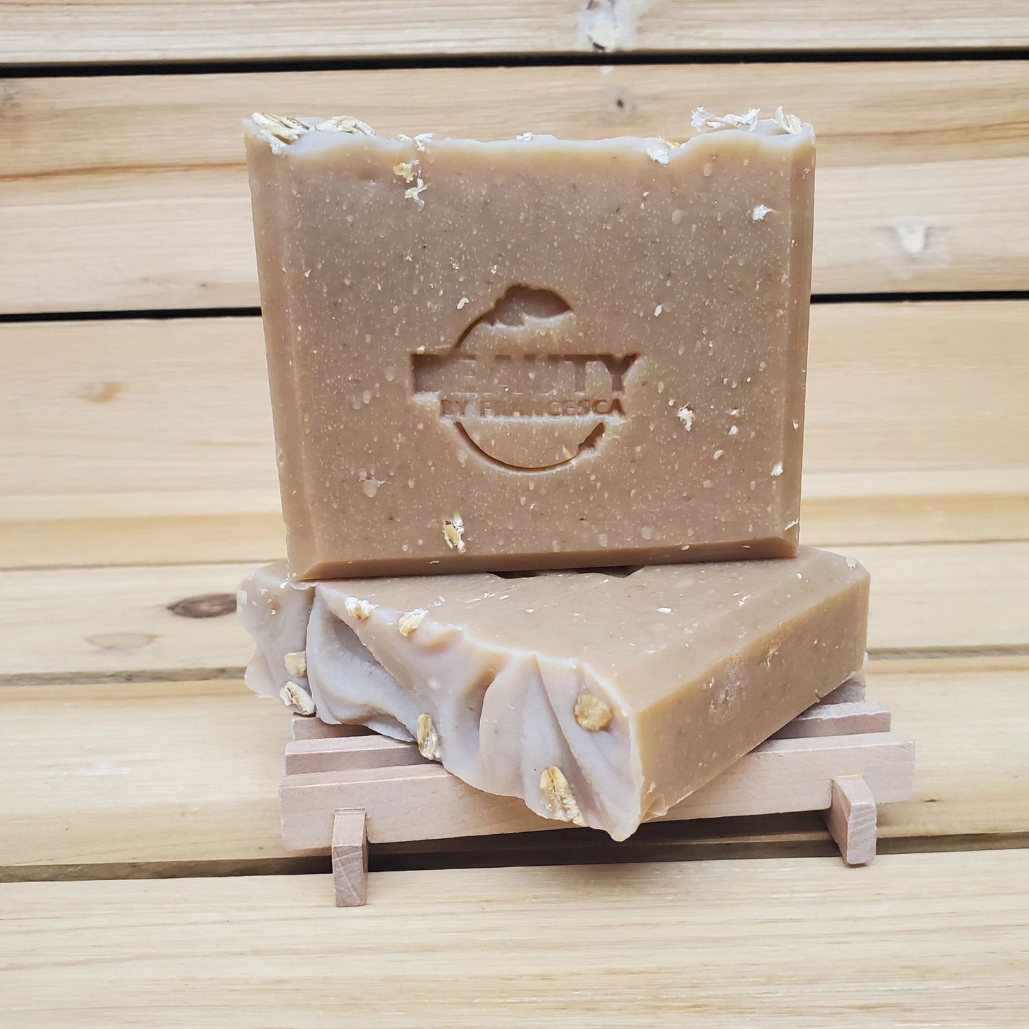 Two bars of honey oatmeal chai soap on a wooden stand with a wooden background