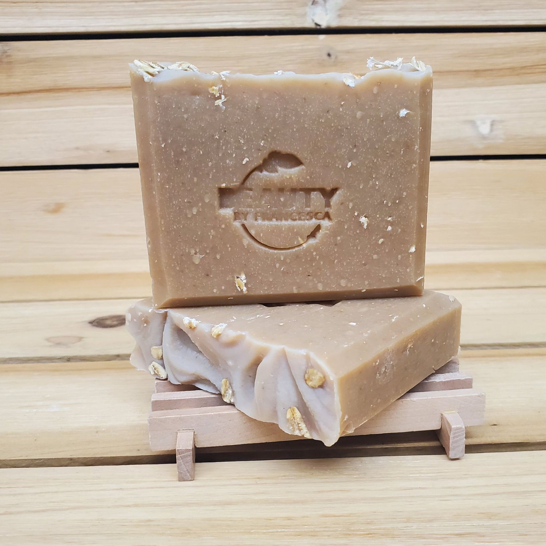 Two bars of honey oatmeal chai soap on a wooden stand with a wooden background