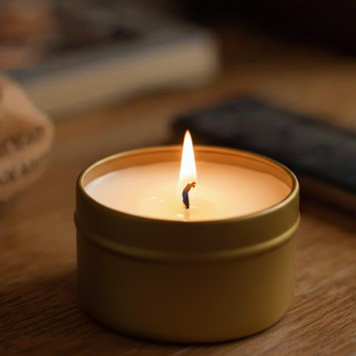 Angel's Breath Candle in a gold tin against a wood background