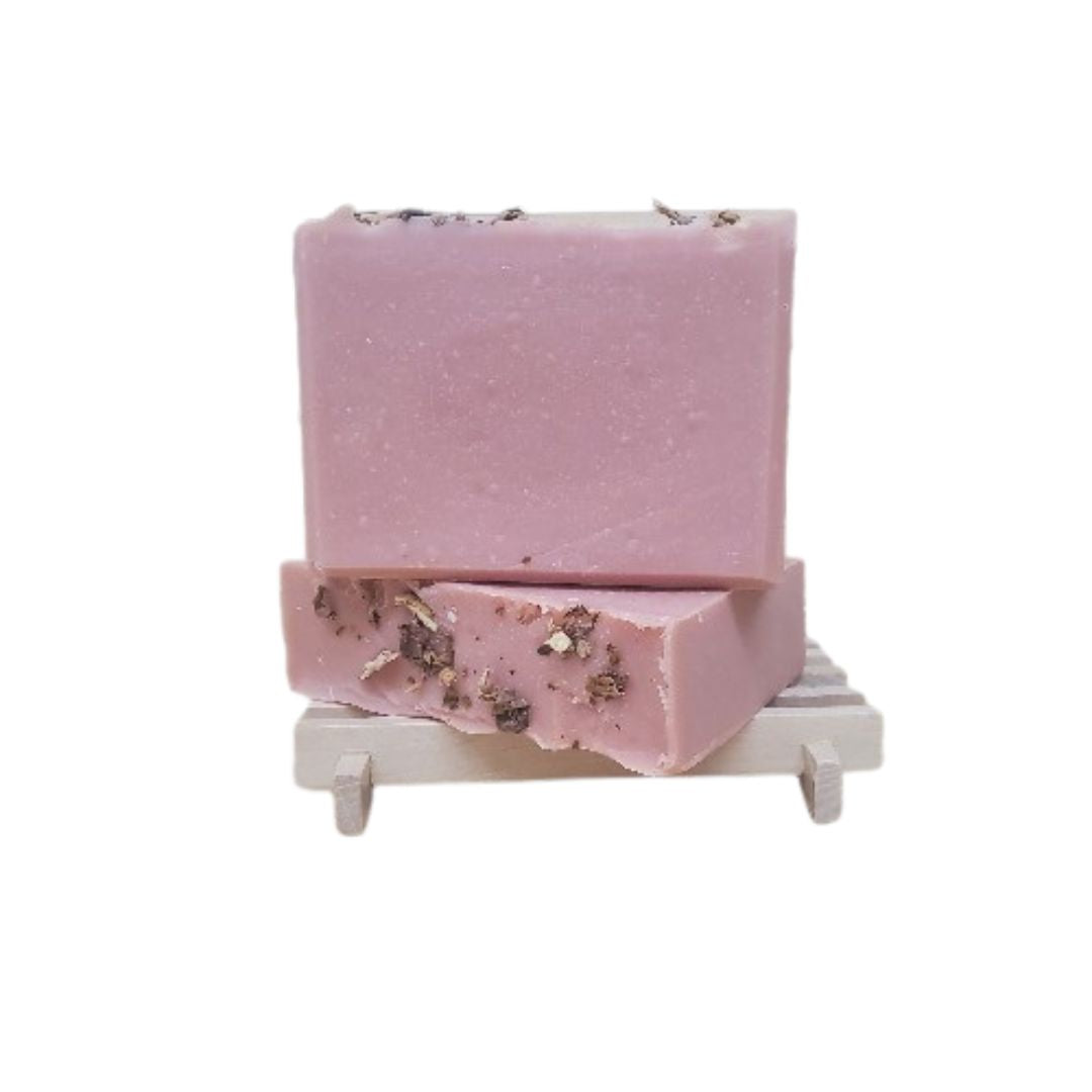 Pink soap bar with decorative roses on top against a white background