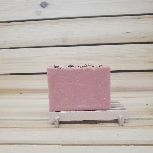 Pink soap bar on a wooden stand with a wooden background