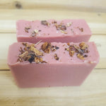 Two pink soap bars decorated with roses on top on a wooden surface