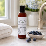 Brilliant Blueberry Lotion next to small bowl of blueberries in front of sunlit window