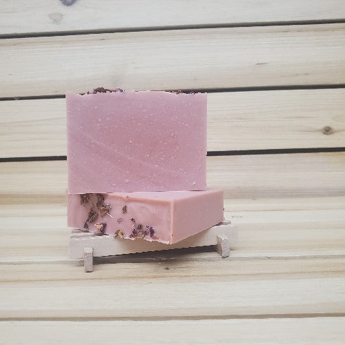 Two pink soap bars on a wooden stand against a wooden background