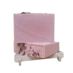 Pink soap bar with decorative rose elements on a white stand against a white background