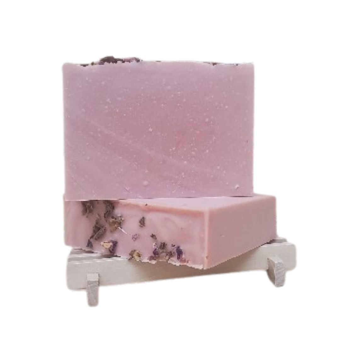 Pink soap bar with decorative rose elements on a white stand against a white background