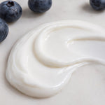 Close up of Brilliant Blueberry Lotion texture next to blueberries