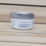 Eucalyptus Spa Soy wax candle in a metal tin with a label on a wooden surface