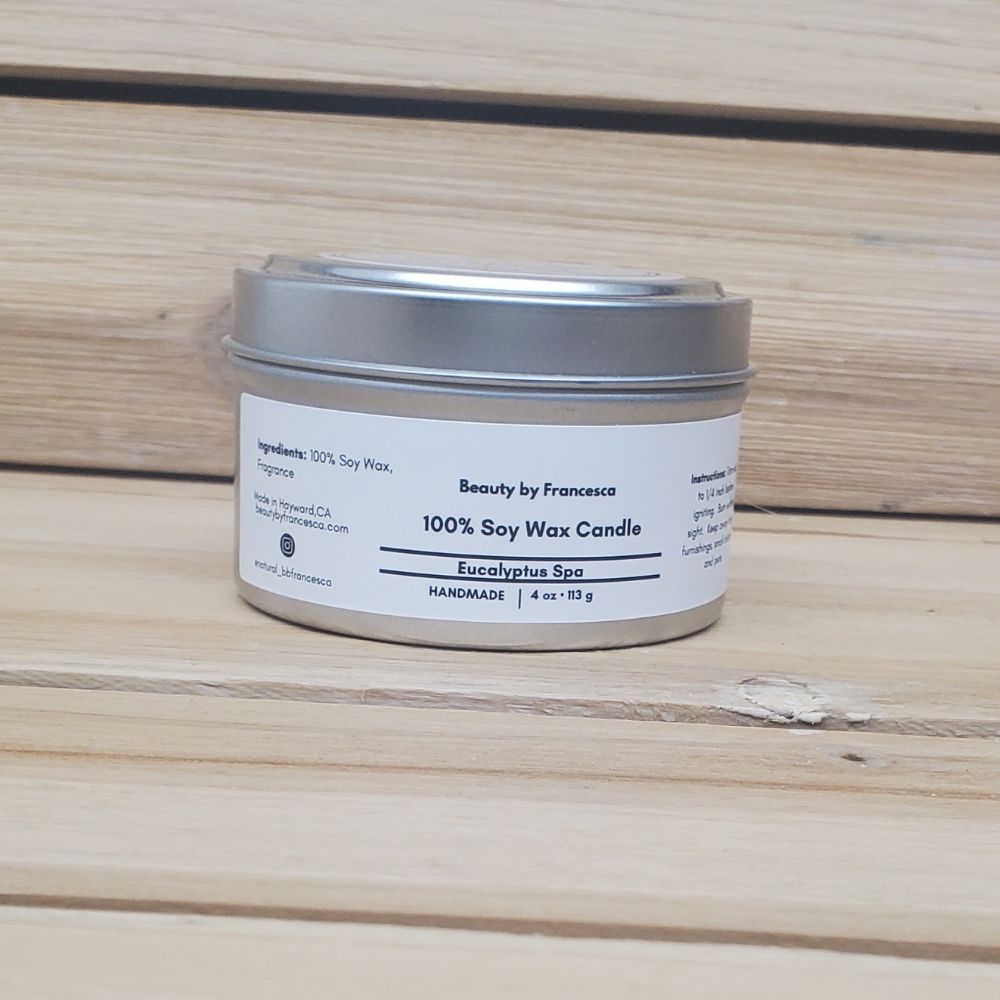 Eucalyptus Spa Soy wax candle in a metal tin with a label on a wooden surface