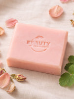 Pink geranium rose soap bar with 'Beauty by Francesca' branding on a textured surface with petals and leaves.