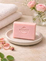 Pink geranium rose soap bar on a white plate with flowers and towels in the background