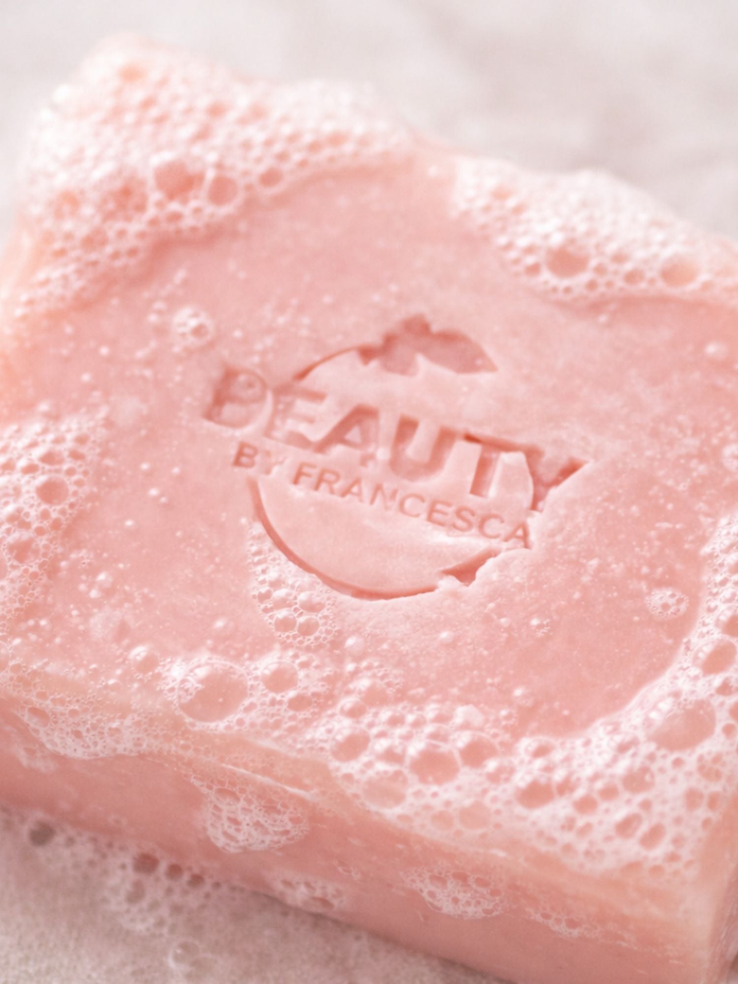 Pink geranium rose soap bar with bubbles and 'Beauty by Francesca' branding on a white background