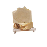 Turmeric-colored vegan handmade soap topped with rose petals, shown on a natural wooden soap dish.