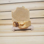 Two bars of turmeric infused soap topped with roses against a wood background