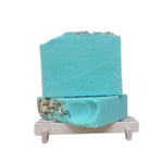 Green soap bar decorated with chamomile on top on a white background