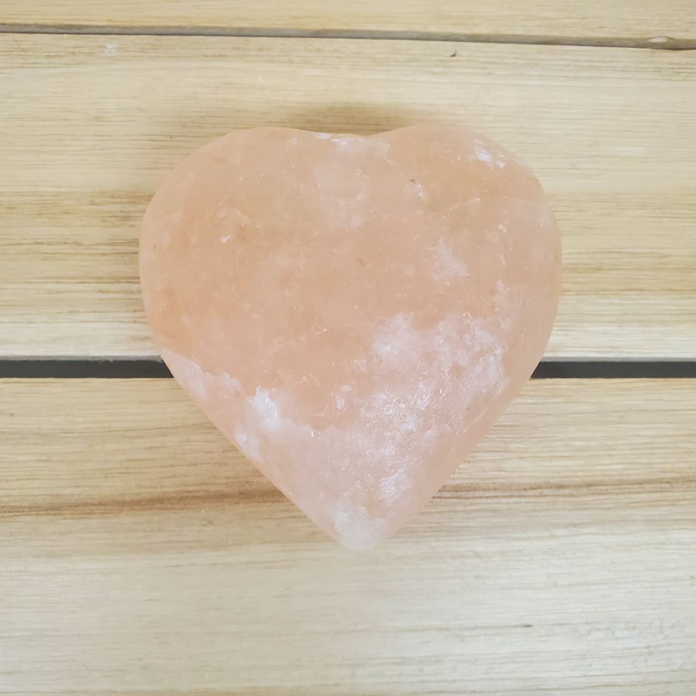 Heart Shaped Pink Himalayan salt Body Massage Stone on a wooden surface 