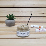 Honey Coconut Lip Scrub next to plant and lip balm open lid