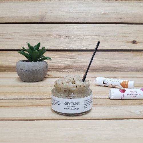 Honey Coconut Lip Scrub next to plant and lip balm open lid