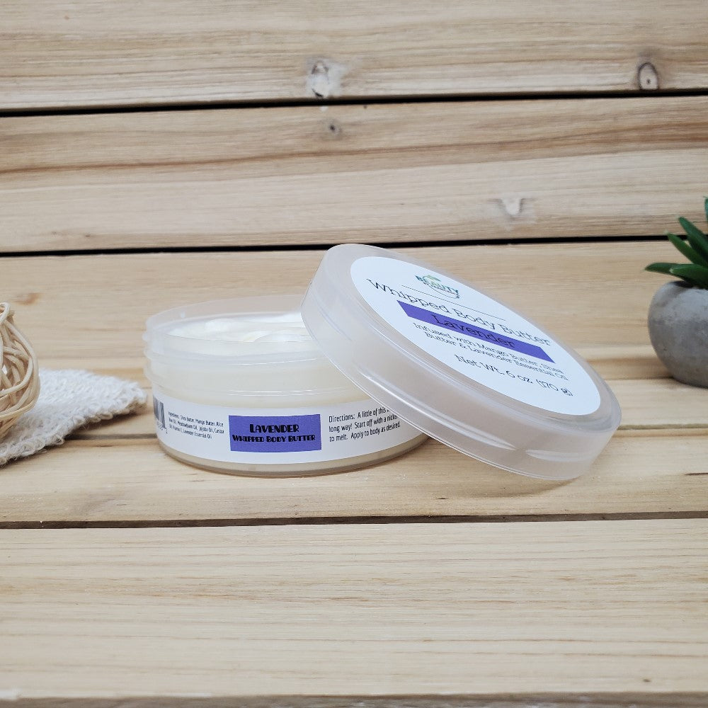 Jar of lavender whipped body butter on a wooden surface with a plant in the background