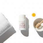 Manuka Honey Lotion bar with a towel and honey dipper on a white background