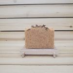 Bar of paprika soap on a wooden soap dish with decorative roses against a wooden background