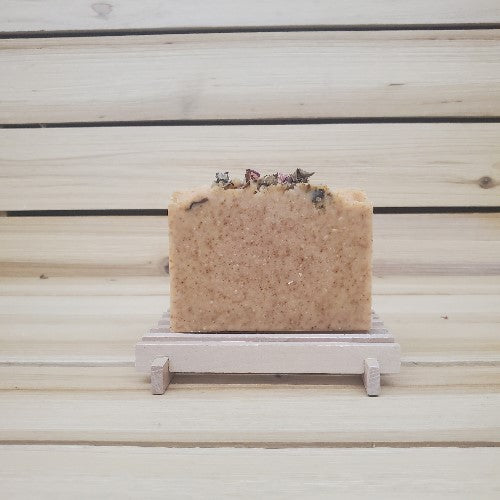 Bar of paprika soap on a wooden soap dish with decorative roses against a wooden background