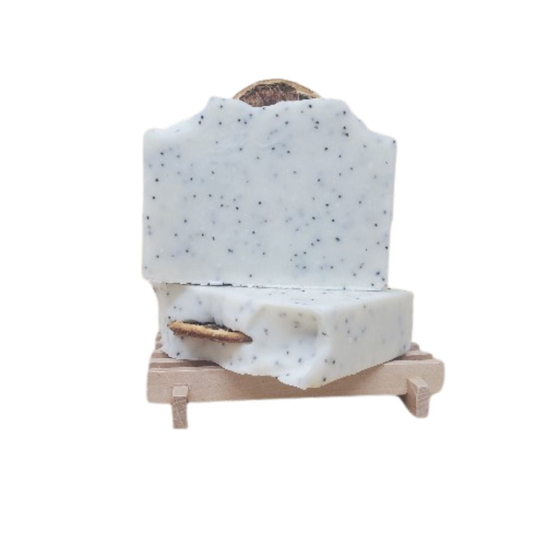 Lemon poppy seed vegan soap bar with dried orange slice on top, shown on a natural wooden soap dish.