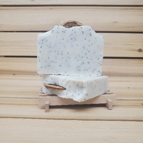 Two bars of Lemon poppy seed vegan soap on a wooden stand against a wooden background