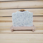 Bar of Lemon poppy seed vegan soap on a wooden stand against a wooden background