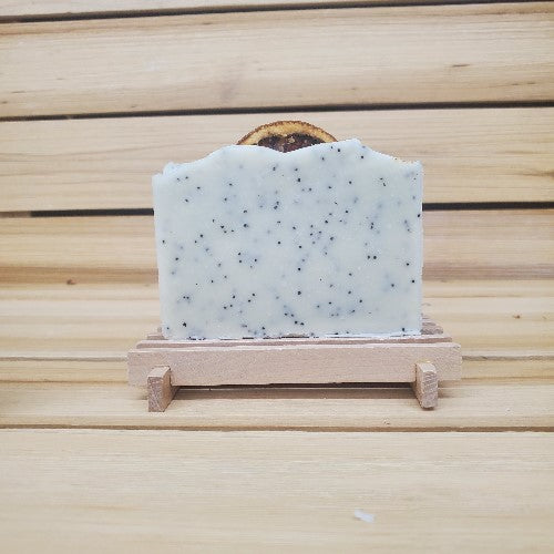 Bar of Lemon poppy seed vegan soap on a wooden stand against a wooden background