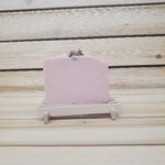 Pink soap bar on a wooden stand against a wooden background