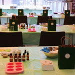 Tables with various items including bottles, a mold, and a bag in a room setting.