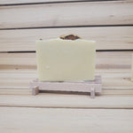 Bar of soap with an orange slice and roses on top on a wooden stand against a wooden background