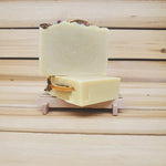 2 bars of soap decorated on top with roses and an orange slice against a wooden background