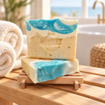 Two Coastal Spa handmade soap bars beside towels in a spa bathroom