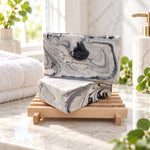 Two bars of Fire and Ice handmade soap on a wooden soap dish in a bright bathroom setting
