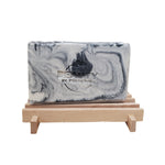 Single bar of Fire and Ice handmade soap with black and white marbling on a wooden soap dish