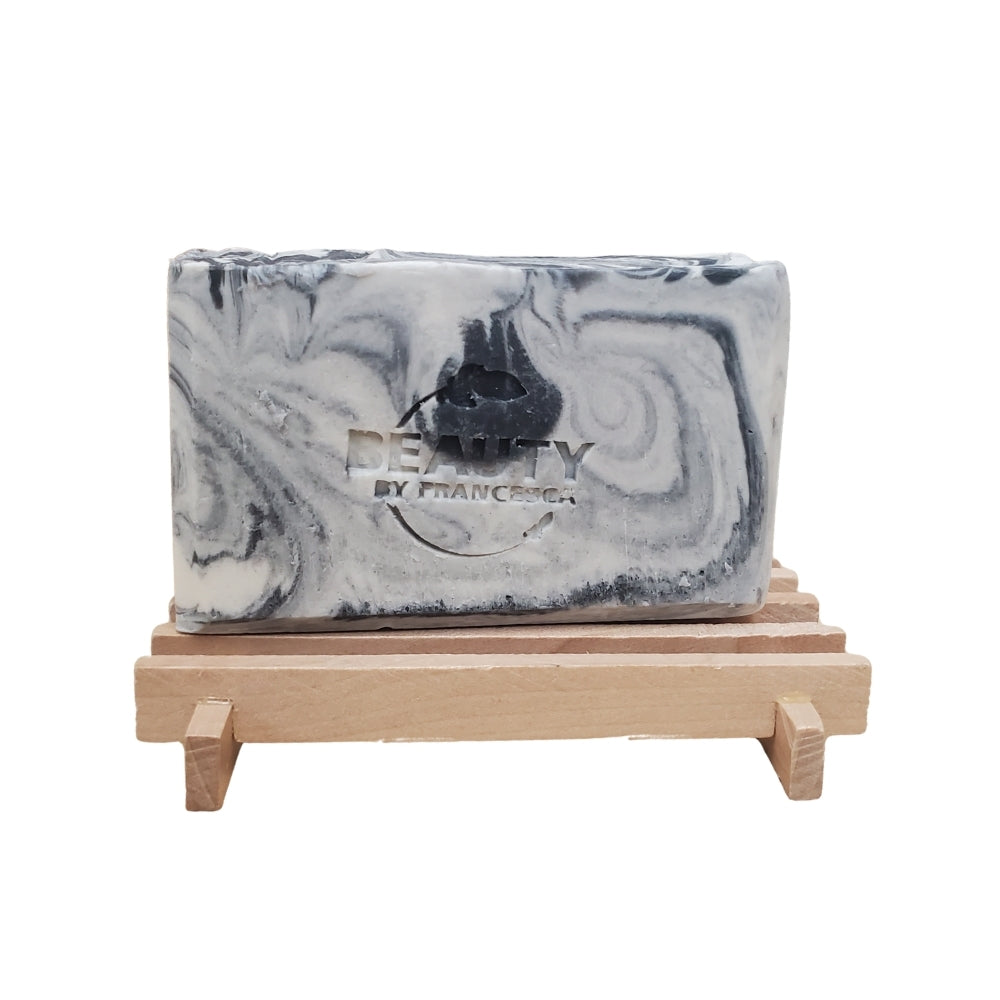 Single bar of Fire and Ice handmade soap with black and white marbling on a wooden soap dish