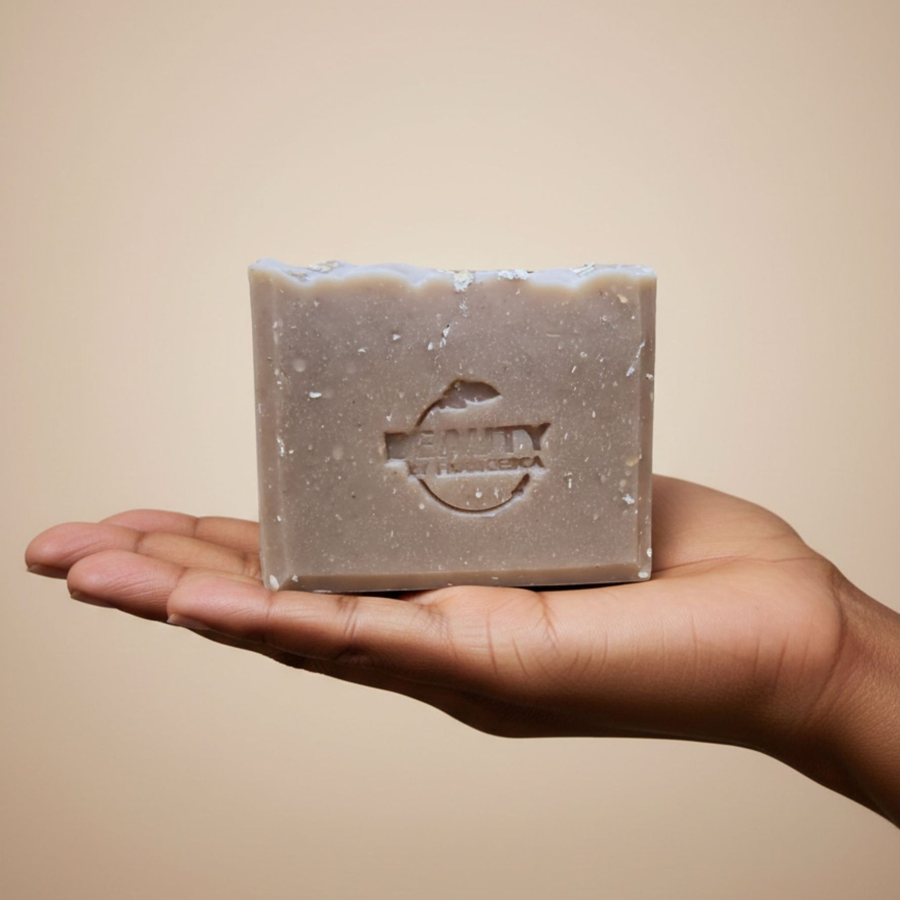 Bar of Beauty by Francesca honey oatmeal chai soap held in a hand against a beige background