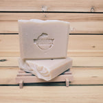 2 bars of lavender orange soap on a soap dish against a wood background