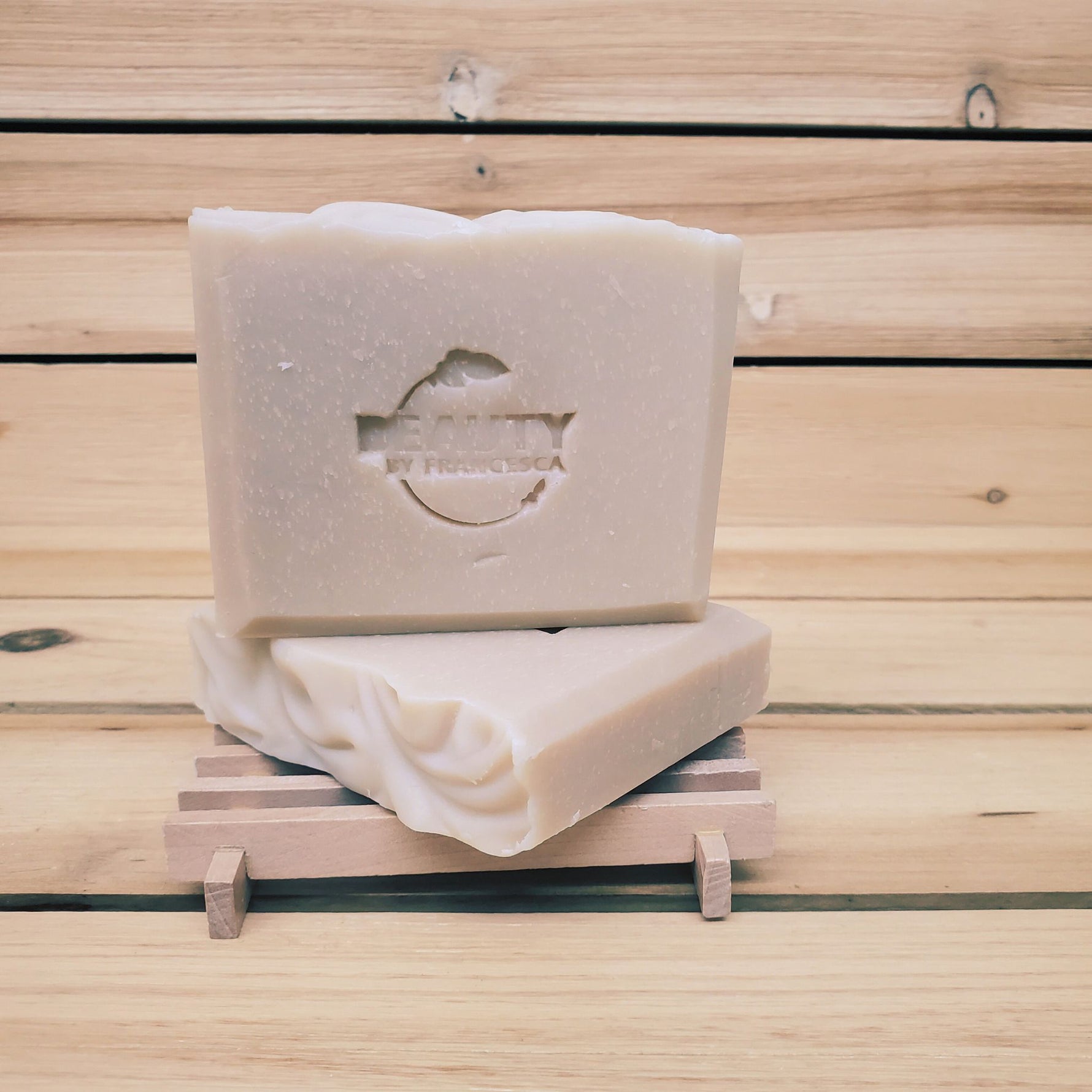 2 bars of lavender orange soap on a soap dish against a wood background