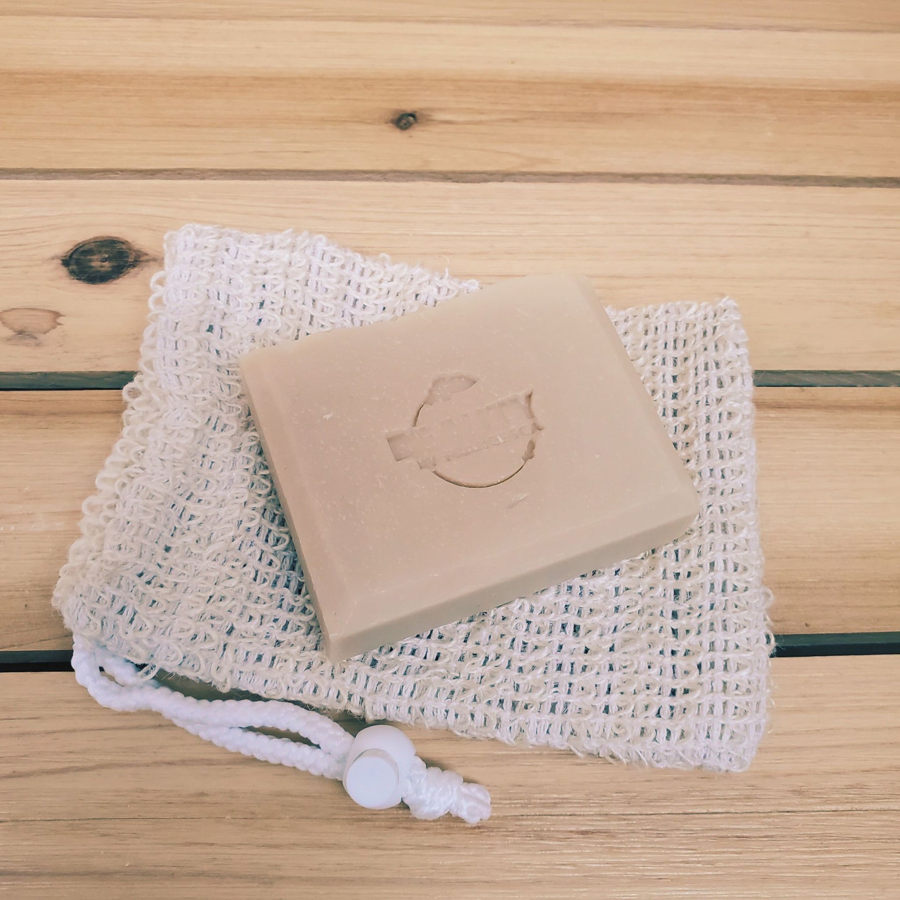 Bar of lavender orange bar soap on a mesh soap bag on a wooden surface
